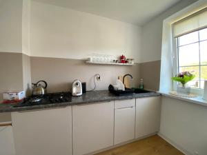a kitchen with white cabinets and a window at PrzyLądek Zdrój Bike Apart in Lądek-Zdrój