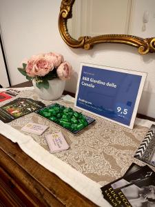 stół z wazonem różowych róż i kartką w obiekcie B&B Giardino delle Camelie w mieście Capannori