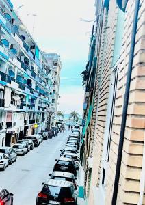 Une rangée de voitures garées dans une rue à côté de grands bâtiments dans l'établissement Piso Lorena 170m playa Wifi aire, à Puerto de Sagunto