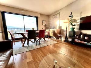 - un salon avec une table, des chaises et une grande fenêtre dans l'établissement Jerickais Appartement à Rueil, à Rueil-Malmaison