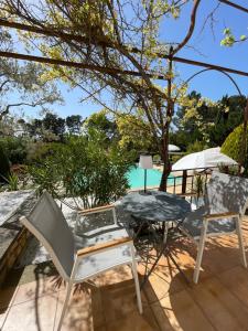 un patio con mesa, sillas y sombrilla en Ô Coeur Des Ocres en Roussillon
