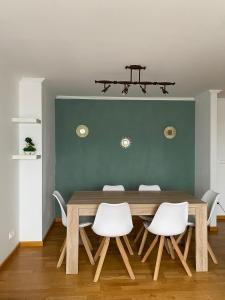 uma sala de jantar com uma mesa de madeira e cadeiras brancas em PRECIOSO ATICO MONDARIZ em Mondariz