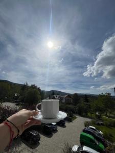 a person holding a cup of coffee on aucer at Karkonoskie Widoki Apartamenty in Karpacz +66 photos