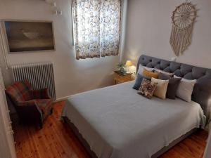 a bedroom with a large bed and a chair at Happy House-Comfortable Apartment in Vathi Square in Meganisi