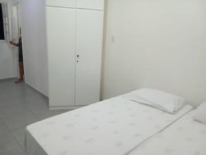 a white bed in a room with white cabinets at Perto do Chevrolet Hall in Recife