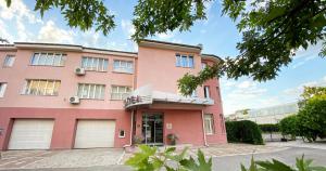 un bâtiment rose avec deux portes de garage dans l'établissement Family Hotel Mania, à Stara Zagora