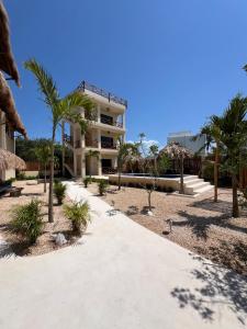 a walkway in front of a building with palm trees at Atenea Holbox in Holbox Island