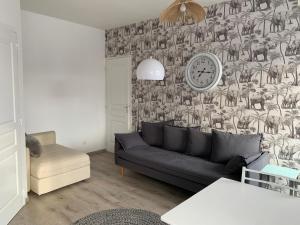 a living room with a couch and a clock on a wall at 36 Maison entière,place parking devant garage in Dunkerque