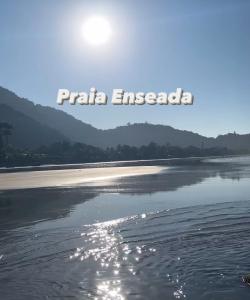 uma vista para uma praia com o sol refletindo na água em Maravilhosa Cobertura Apto com Vista para o Mar - Praia da Enseada em Ubatuba em Ubatuba