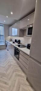 uma cozinha com electrodomésticos de aço inoxidável e armários brancos em Luxury Penthouse - Central Location - 2 Bed em Leeds