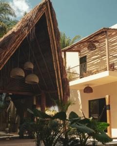 a house with a thatched roof and a balcony at Nikau Hotel El Cuyo - Adults Only in El Cuyo