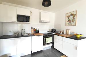 een keuken met witte kasten en een fornuis met oven bij Spacious apartment with garden and parking slot in Bordeaux