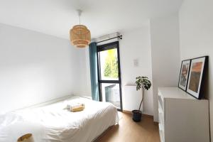 een witte slaapkamer met een bed en een raam bij Spacious apartment with garden and parking slot in Bordeaux
