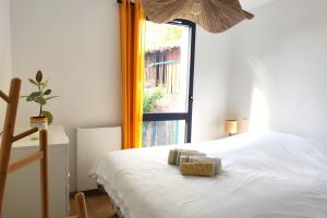 een slaapkamer met een wit bed en een raam bij Spacious apartment with garden and parking slot in Bordeaux