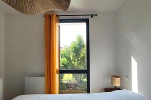 een slaapkamer met een raam met een oranje gordijn bij Spacious apartment with garden and parking slot in Bordeaux