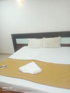 a bed with white sheets and pillows on it at Bkm guest room in Chennai