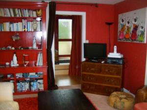 a living room with red walls and a tv on a dresser at un amour de maison in Le Conquet