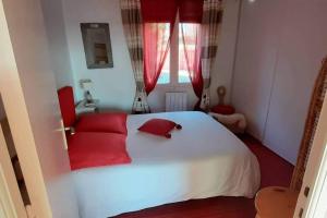a bedroom with a white bed with red pillows at un amour de maison in Le Conquet