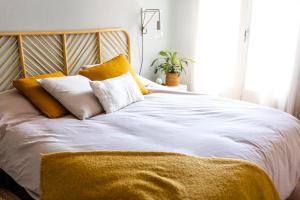 - un lit avec des oreillers jaunes et blancs dans l'établissement Hôtel New Palmarium, à Amélie-les-Bains-Palalda