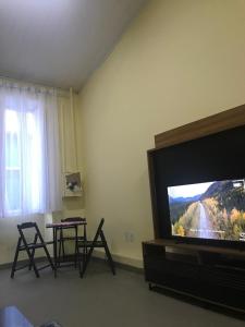 uma sala de estar com televisão e uma mesa com cadeiras em Casa Amarela no Coração de Lençois em Lençóis