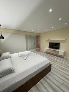 um quarto com uma grande cama branca e uma televisão de ecrã plano em HOME 12 em Librazhet