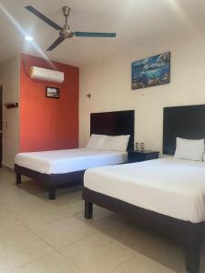 2 camas en una habitación con una pared roja en Apartamentos Luna Turquesa Bacalar - Gratis Renta Bicicletas, en Bacalar