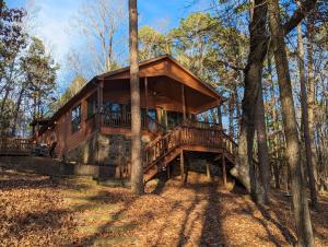 a tree house in the woods with a large deck at Greers Ferry Lake Cabin in Heber Springs