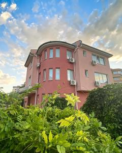 um edifício rosa com arbustos à frente em Family Hotel Mania em Stara Zagora