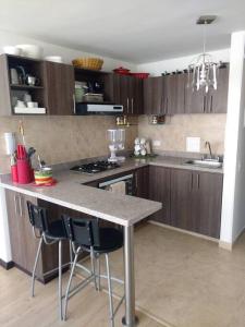 una cocina con armarios de madera y una barra con sillas en Cómodo apartamento en Tocancipa, en Tocancipá