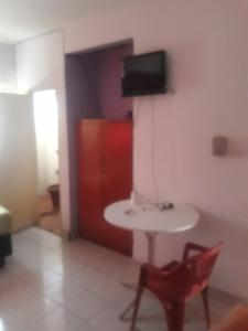 Zimmer mit einem Tisch und einem TV an der Wand in der Unterkunft San Miguel Hostal in Villarrica