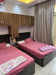 2 camas en un dormitorio con sábanas rosas en pharma beach resort x rent قرية الصيادلة بلطيم, en Al Ḩammād