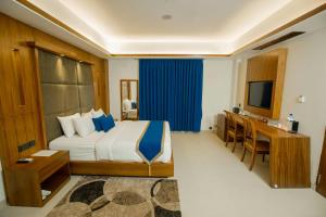 a bedroom with a bed and a desk and a television at Hotel Aurora Mirage Delhi in New Delhi