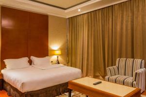 Hotel Aurora Mirage Delhi في نيودلهي: غرفه فندقيه بسرير وكرسي