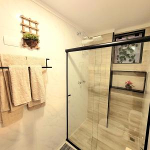 a bathroom with a glass shower stall and towels at Apartamento 16 - (850 mt do Centro) - 2 Banheiros in Poços de Caldas