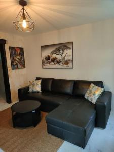 sala de estar con sofá de cuero negro y mesa en Charmante maison, en Niort