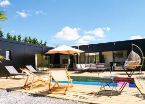 a group of chairs and an umbrella next to a pool at Evasion tropicale in Bretteville-sur-Odon