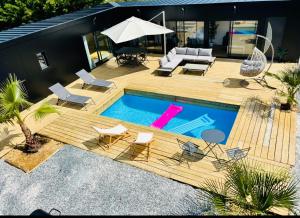 een achtertuin met een zwembad en een terras met stoelen en een parasol bij Evasion tropicale in Bretteville-sur-Odon
