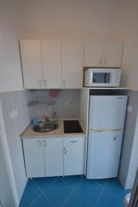małą kuchnię ze zlewem i kuchenką mikrofalową w obiekcie Apartments Morinj w mieście Donji Morinj