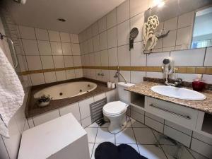 ein Badezimmer mit einer Badewanne, einem WC und einem Waschbecken in der Unterkunft Loft Central in Jaraguá do Sul