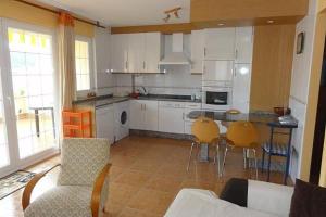 cocina con armarios blancos, mesa y sillas en Apartamento Playa de Quenxe - Corcubión, en Corcubión