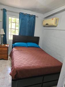a bedroom with a bed with a red comforter and a window at oasis with pool near Panama Canal in Panama City