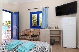 a room with a bed and a desk with a television at Niko's Beach Suites ΔΥΟ in Agia Marina Aegina