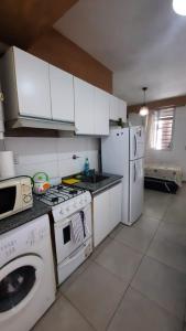 La cuisine est équipée de placards blancs, d'une cuisinière et d'un lave-vaisselle. dans l'établissement Departamento Citrino, à Godoy Cruz