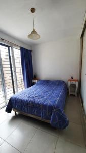 a bedroom with a blue bed in a room with windows at Departamento Citrino in Godoy Cruz