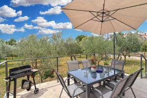 a patio with a table and a grill and an umbrella at Ferienhaus für 4 Personen ca 74 qm in Medulin, Istrien Südküste von Istrien in Medulin