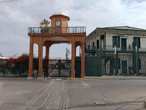 a gate with a clock tower in front of a building at 2 de Mayo Studio 1 in Tacna