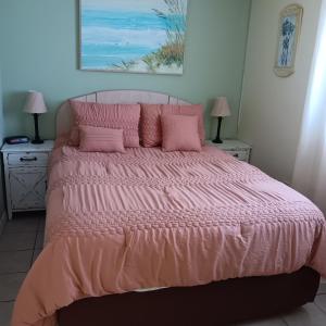a bedroom with a large bed with pink sheets and pillows at Cozy Beach Getaway in Cape Canaveral