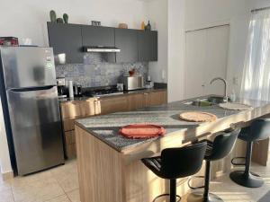 a kitchen with a counter with chairs and a refrigerator at Charming and Cozy Condo San Blas in Puerto Vallarta