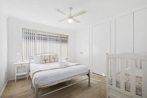 a white bedroom with a bed and a ceiling fan at Lakeview Tranquility Budgewoi in Budgewoi