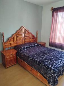a bedroom with a wooden bed with a blue comforter at Casa María Sabina in San Juan del Río